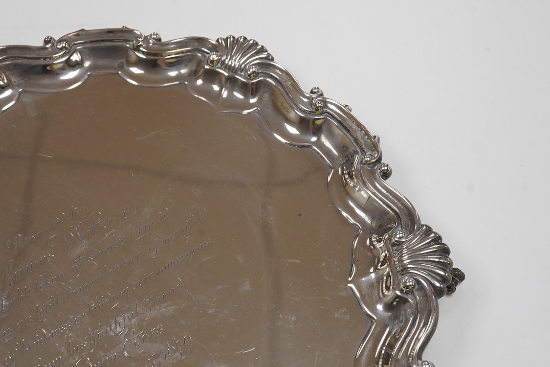 A late Victorian silver salver, with shell and scroll border and engraved inscription, on three claw and ball feet, Mappin Brothers, Sheffield, 1896, 26.4cm, 15.2oz.